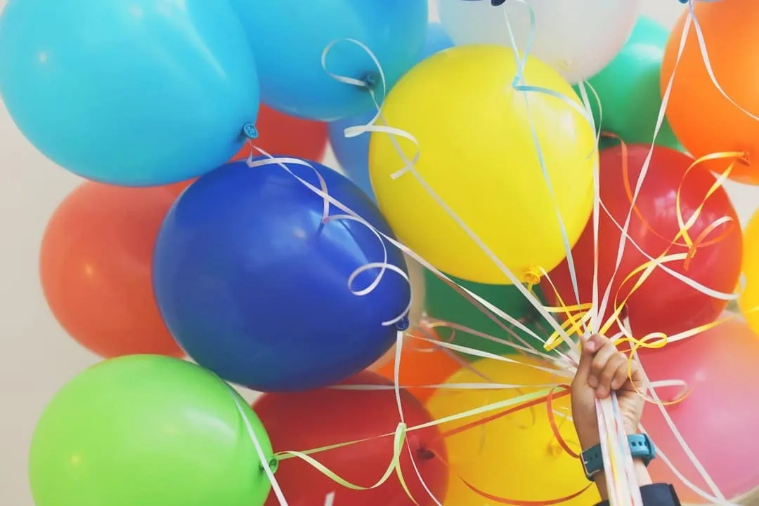 Bos gekleurde ballonnen met krullende linten, vastgehouden door een hand