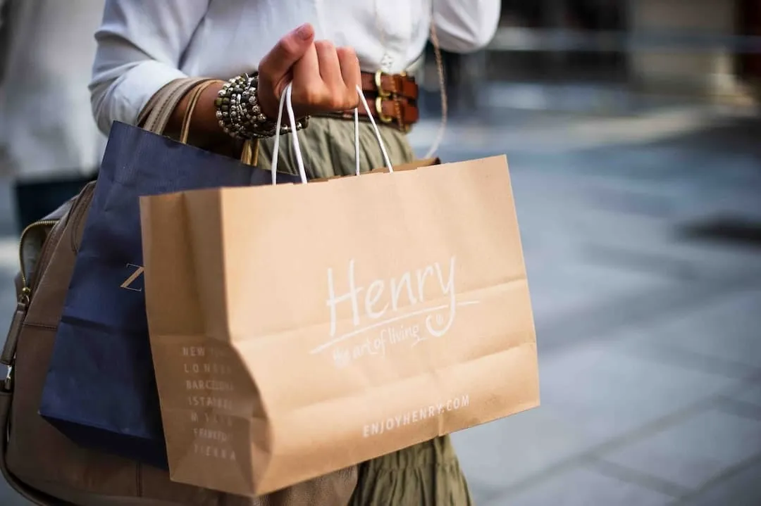 Vrouw met papieren draagtassen van winkels in haar hand op een winkelstraat