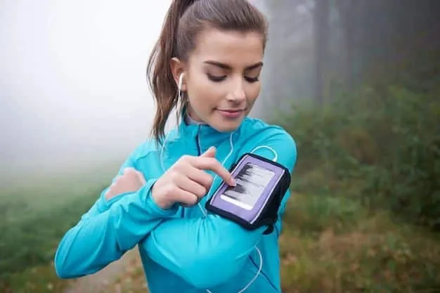 Vrouw in een sportjas bedient haar telefoon in een armband tijdens het hardlopen in de mist