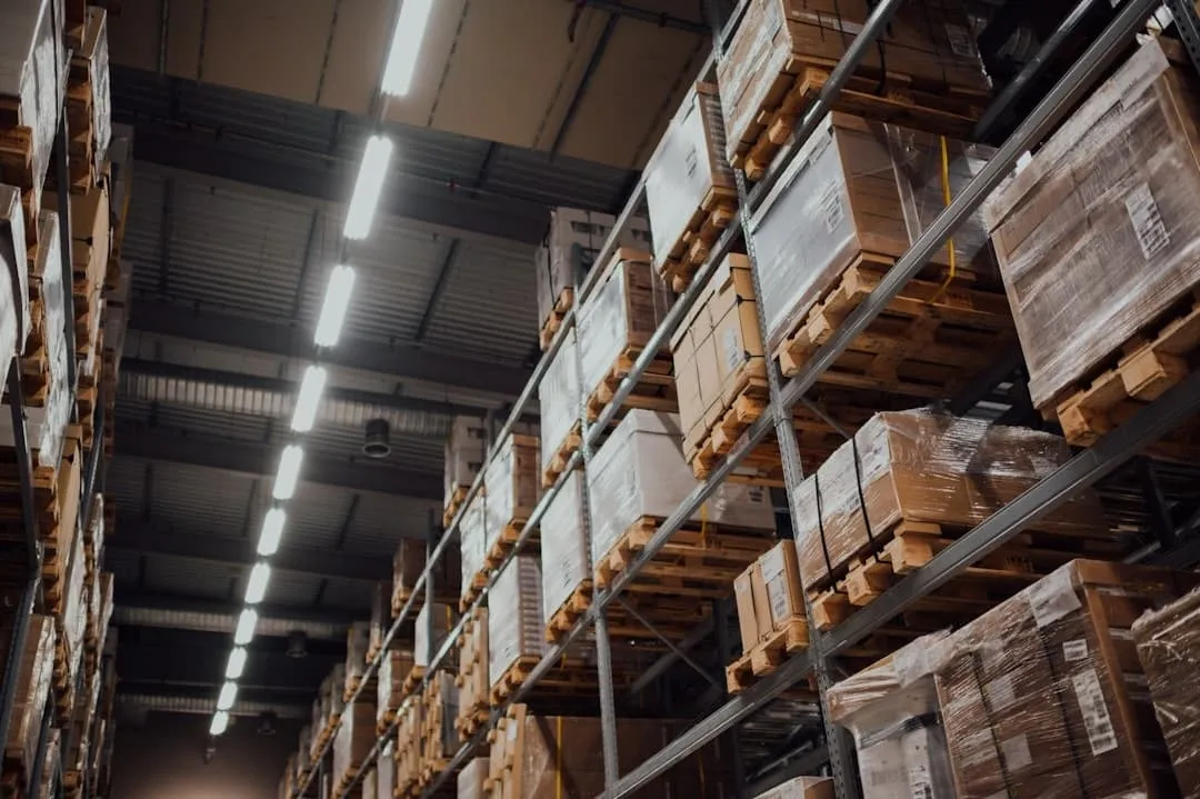 Magazijn met hoge stellingen vol pallets en dozen onder een lange tl-balk