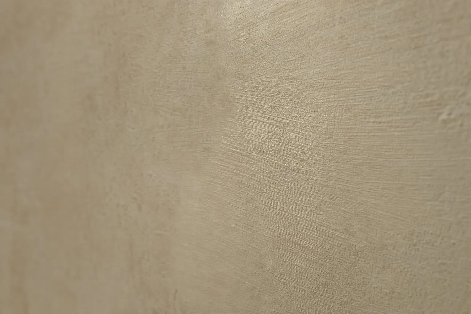 Detail van een kalkverfmuur waarop de kruislingse kwaststreken bij zijlicht zichtbaar zijn